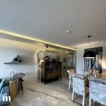 A contemporary dining room with marble floors and a sizable painting.